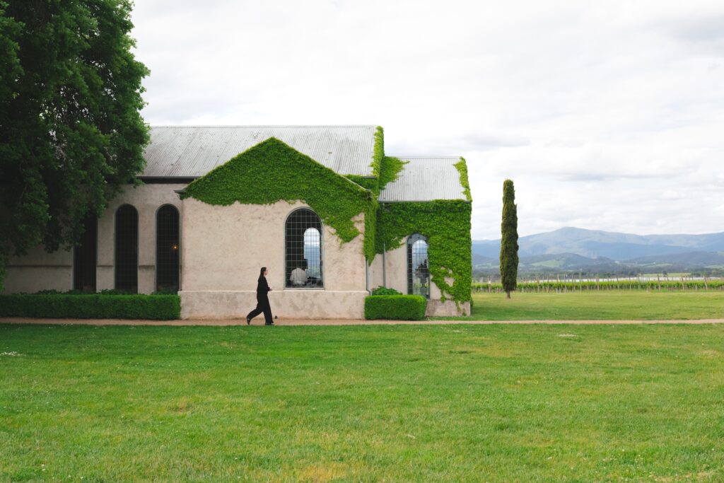 A lady walking past the chapel at Stones of the Yarra Valley on a cloudy day