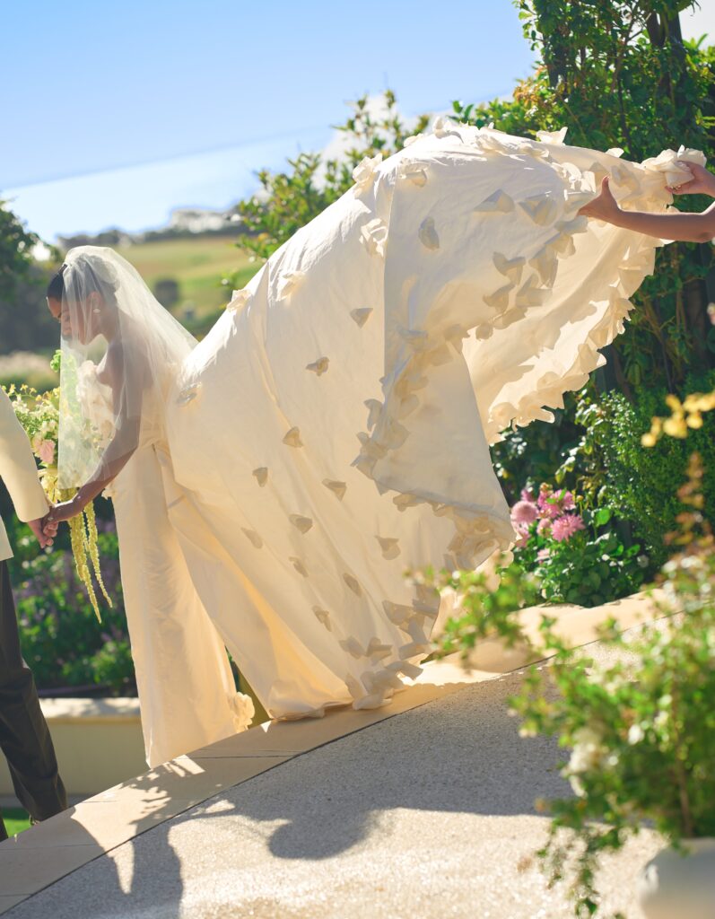 A bridesmain fluffs the brides dress during her wedding ceremony at Sunnyside Events