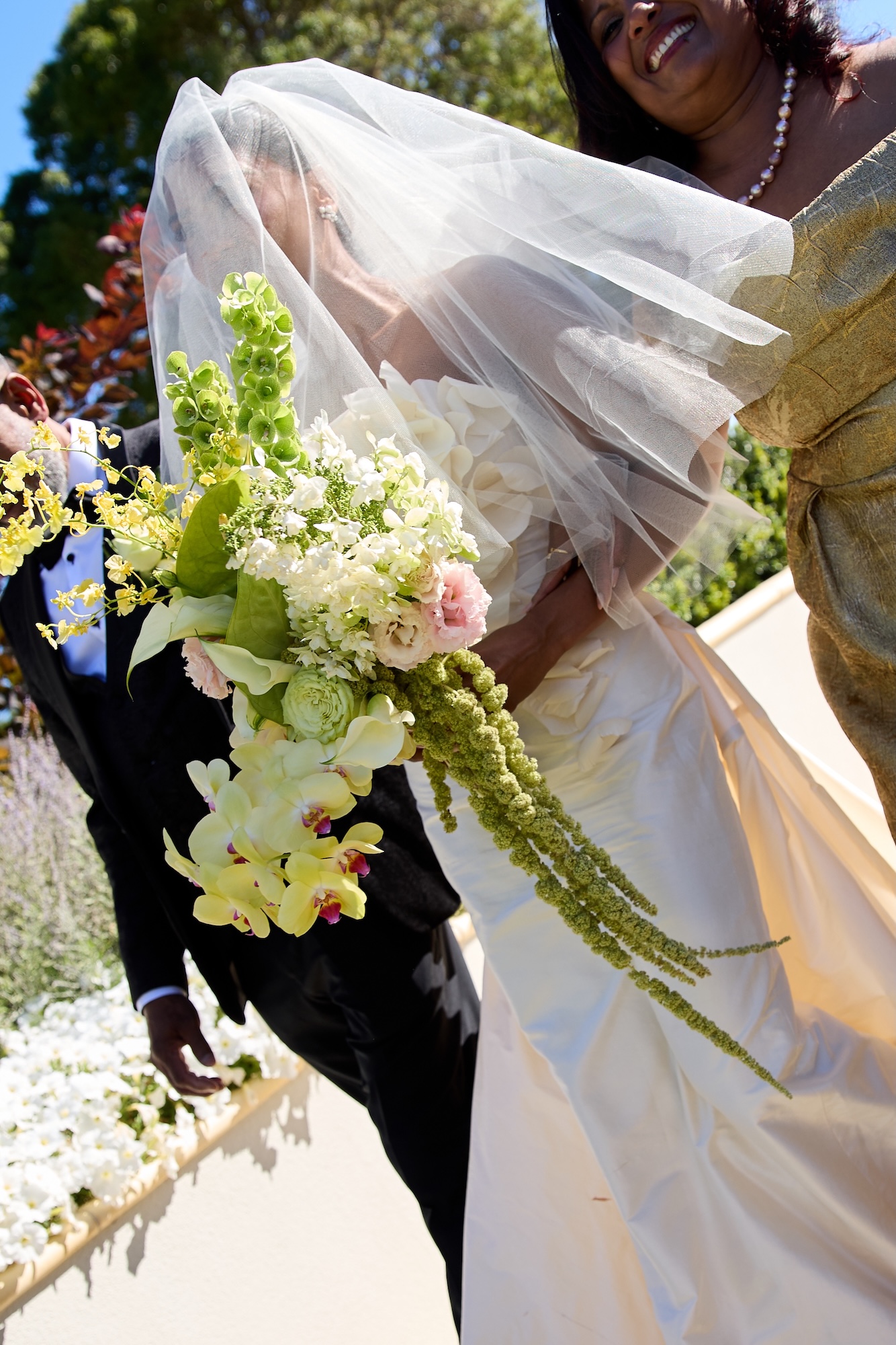 bride is being walked down the aisle with her parents as she is covered in a veil at Sunnyside events