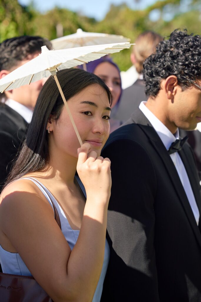a lady watching the bride walk down the aisle on a sunny wedding day